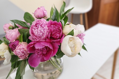 Photo of Vase with bouquet of beautiful peonies on table in room, space for text