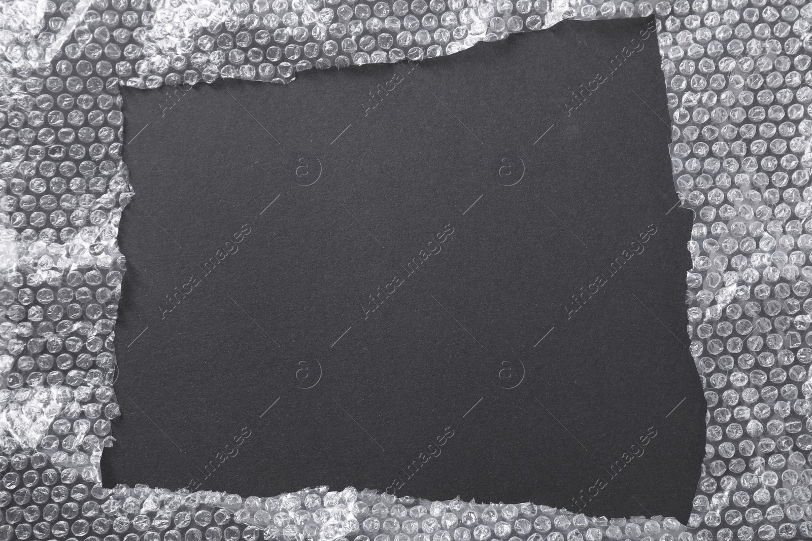 Photo of Frame made of bubble wrap on black background, top view. Space for text