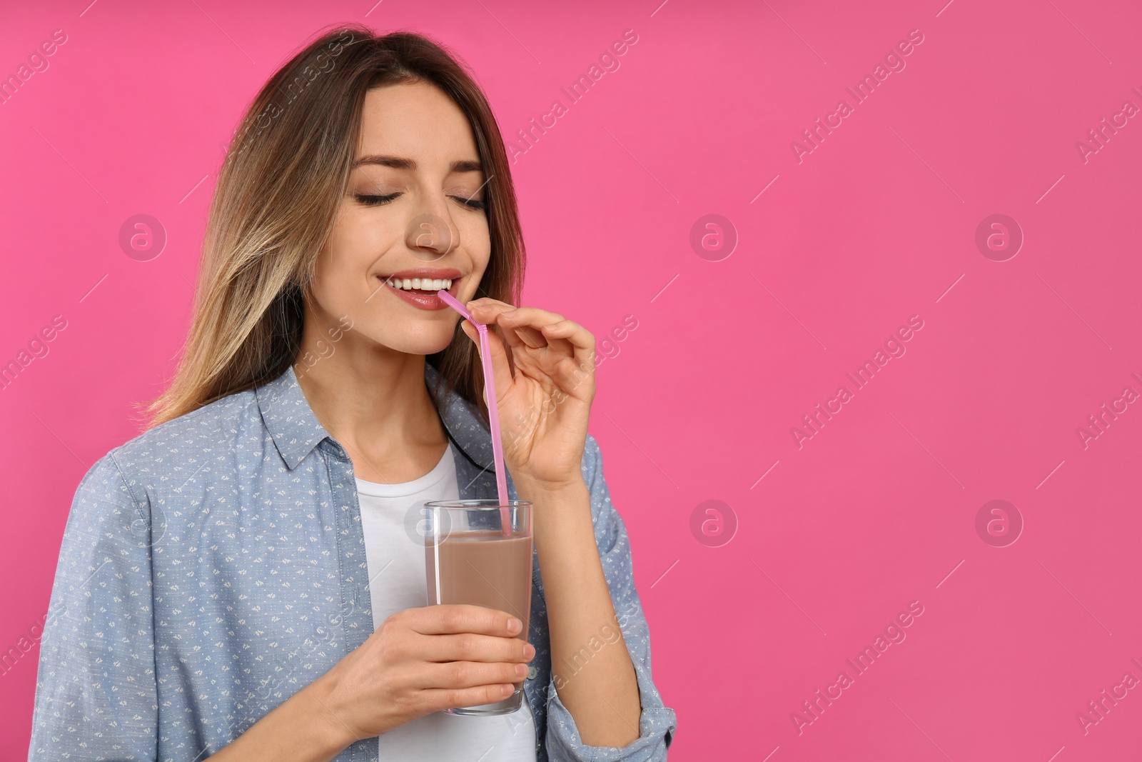 Photo of Young woman drinking chocolate milk on pink background. Space for text