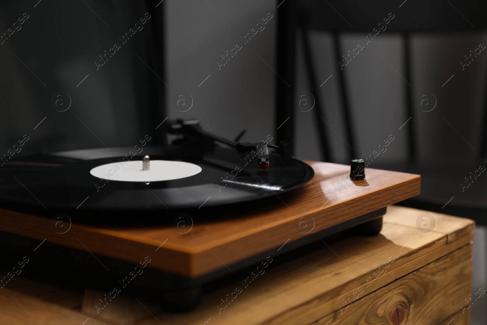 Photo of Stylish turntable with vinyl disc on wooden crate in room, closeup