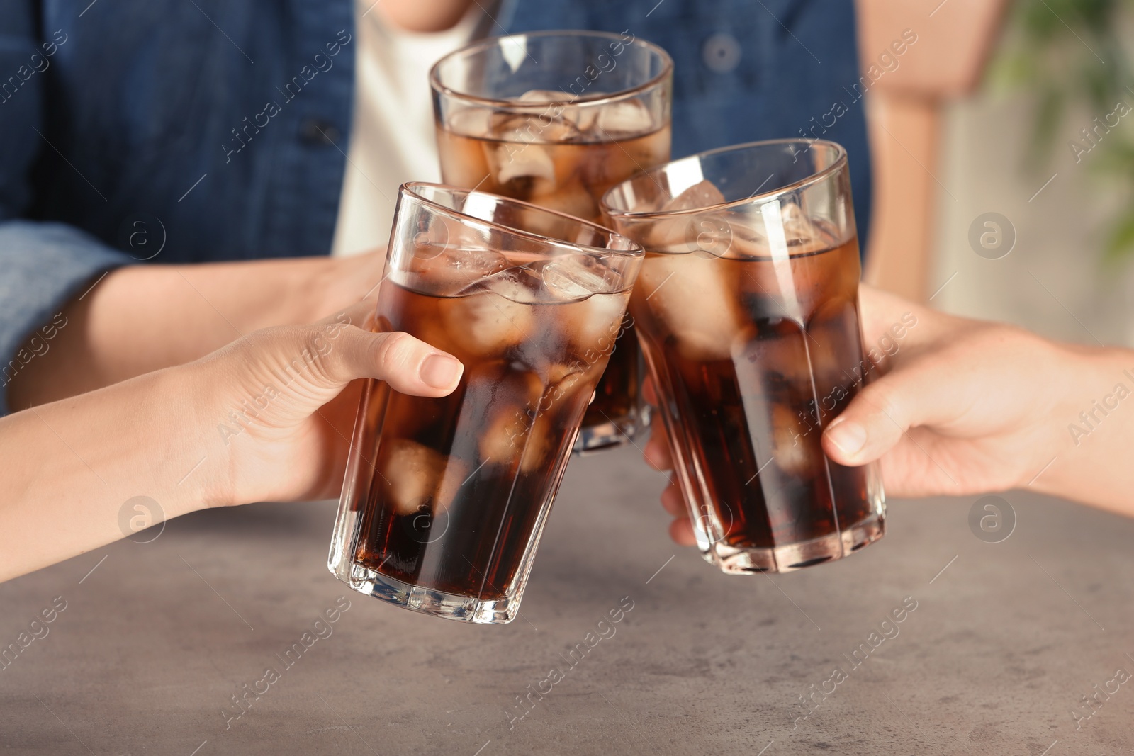 Photo of Friends with glasses of tasty refreshing cola at table, closeup view