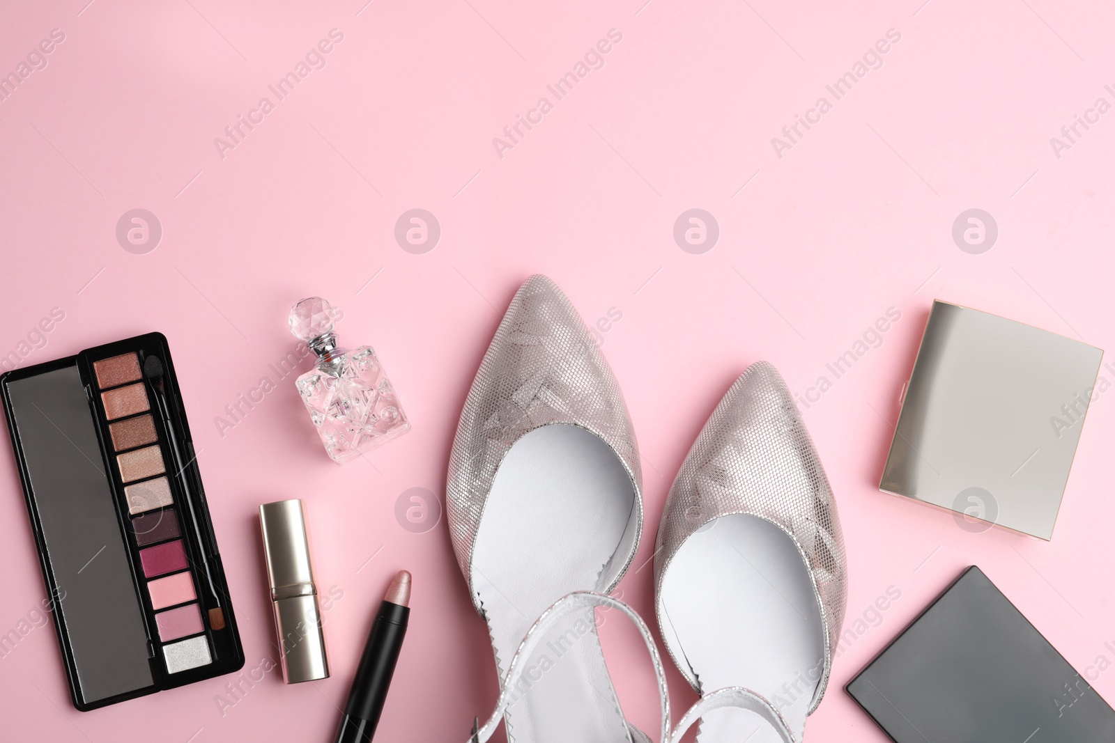 Photo of Stylish silver female shoes and decorative cosmetics on pink background, flat lay