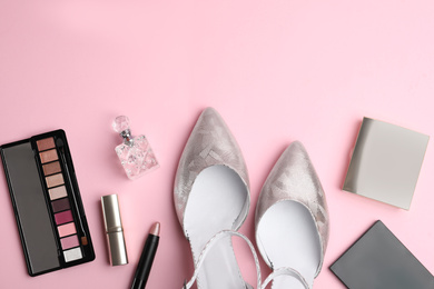 Stylish silver female shoes and decorative cosmetics on pink background, flat lay