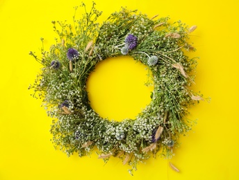Photo of Beautiful wreath made of wildflowers on yellow background, top view