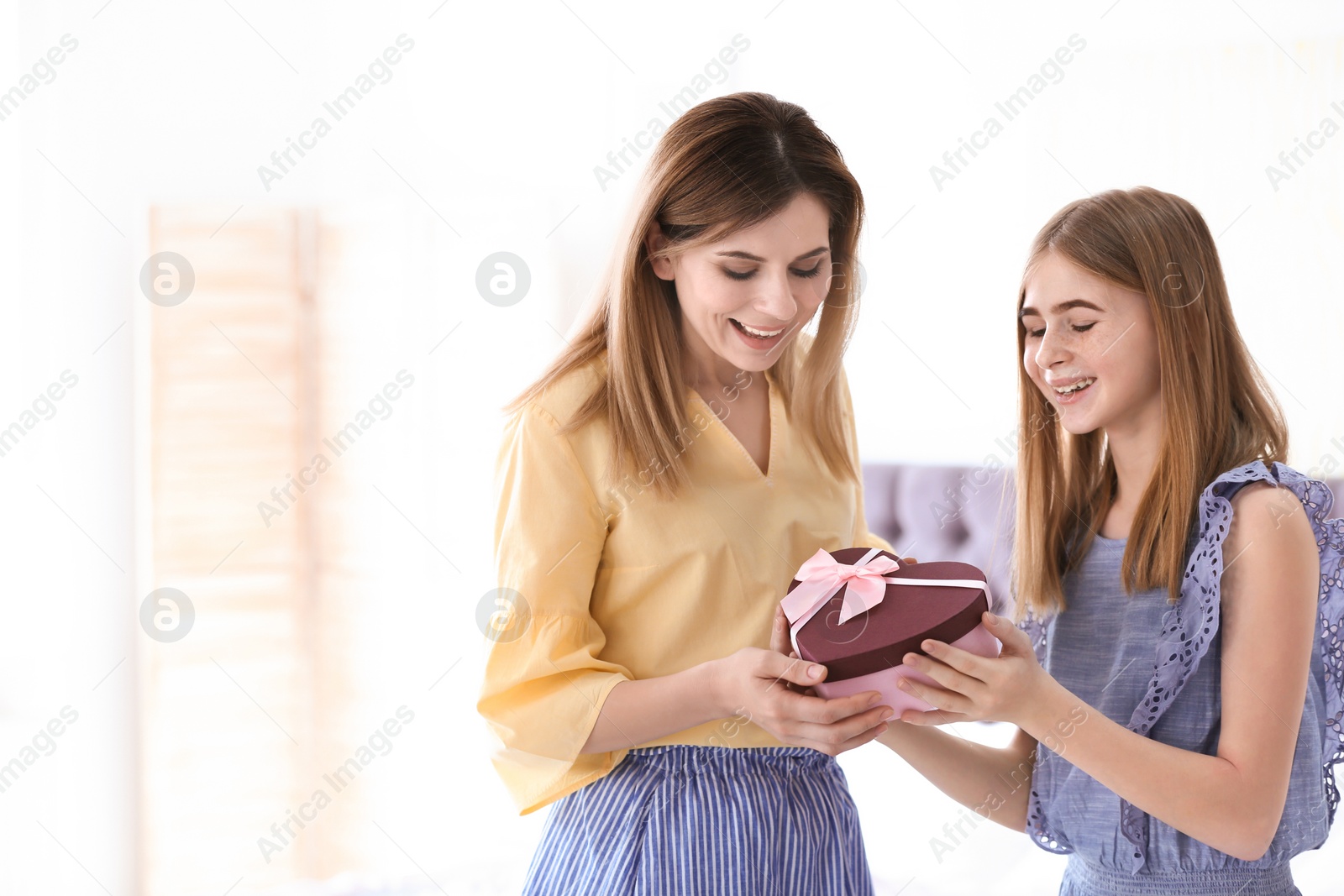 Photo of Teenage daughter congratulating happy woman on Mother's Day at home