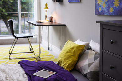Modern teenager's room interior with comfortable bed, workplace and stylish design elements