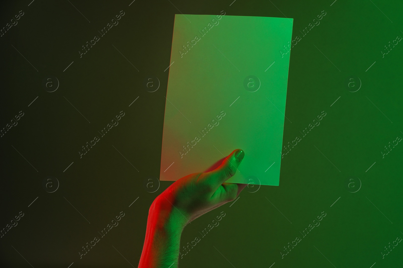 Photo of Man holding sheet of paper on green background, closeup and space for text. Color tone effect