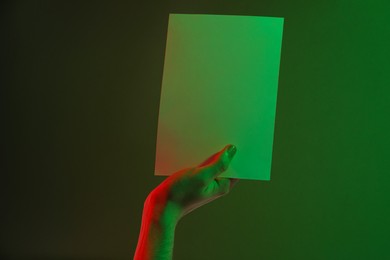 Photo of Man holding sheet of paper on green background, closeup and space for text. Color tone effect