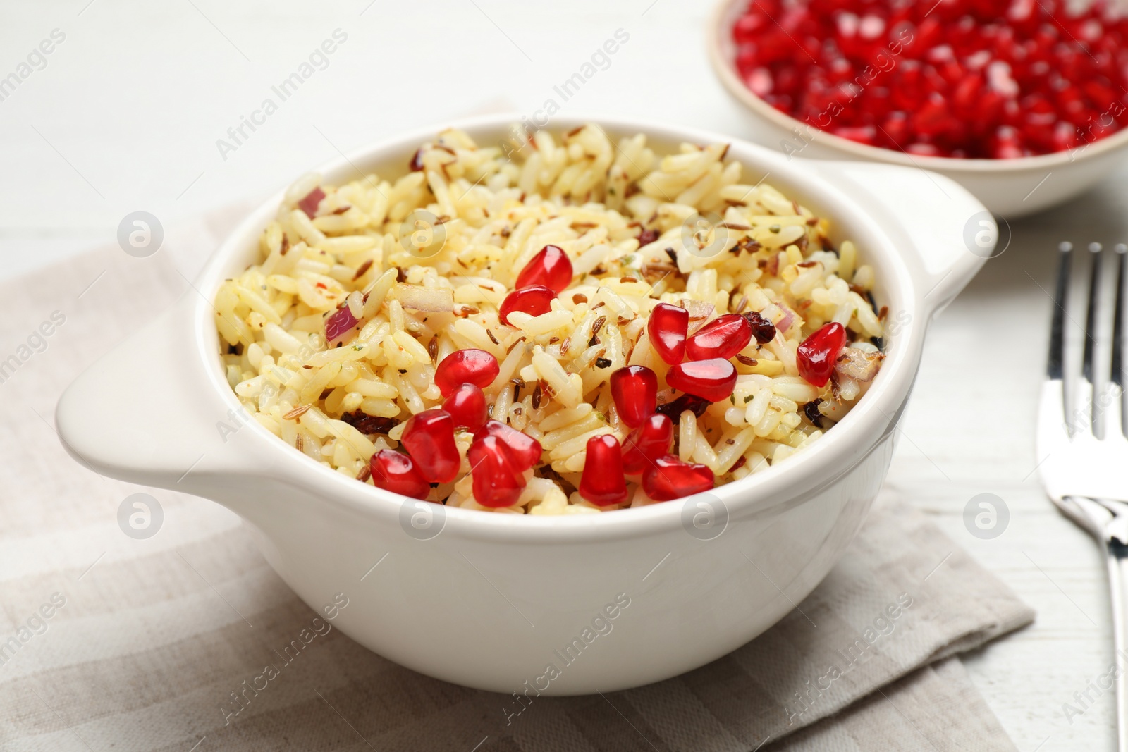 Photo of Tasty rice pilaf with pomegranate grains on table, closeup