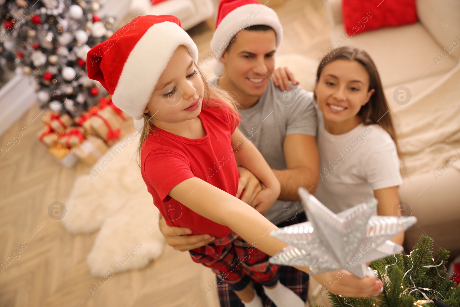 Photo of Family decorating Christmas tree with star topper in room, above view