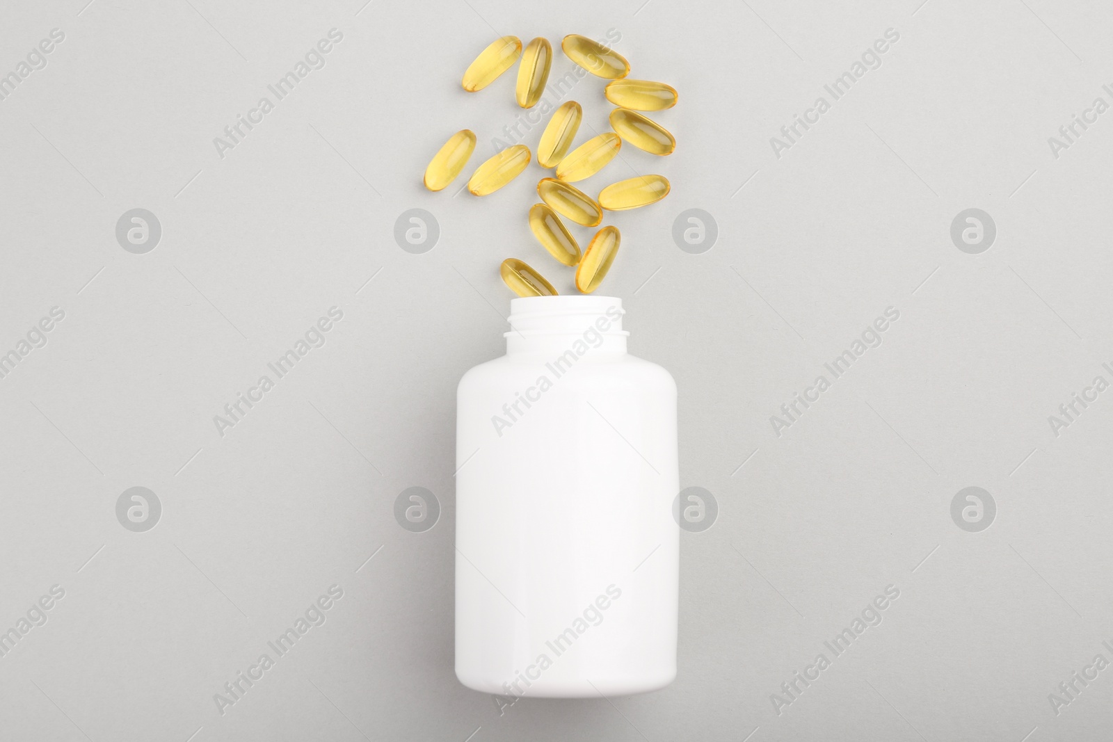 Photo of Bottle and vitamin capsules on light grey background, top view