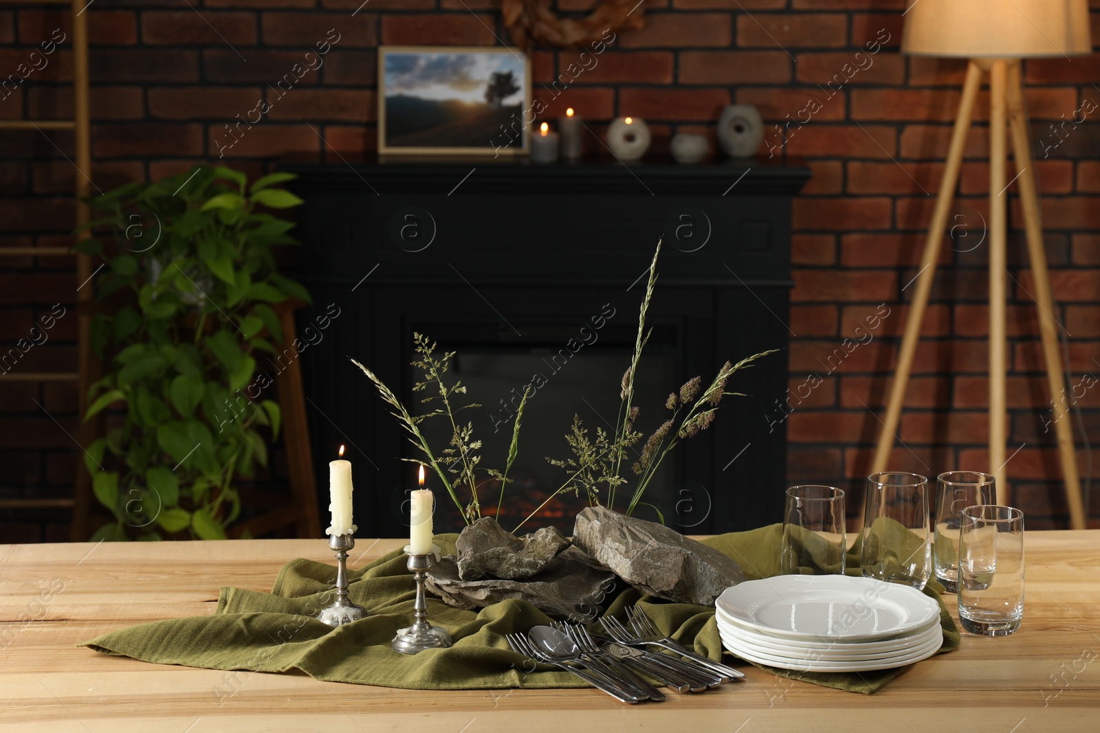 Photo of Clean dishes, stones and plants on wooden table in stylish dining room