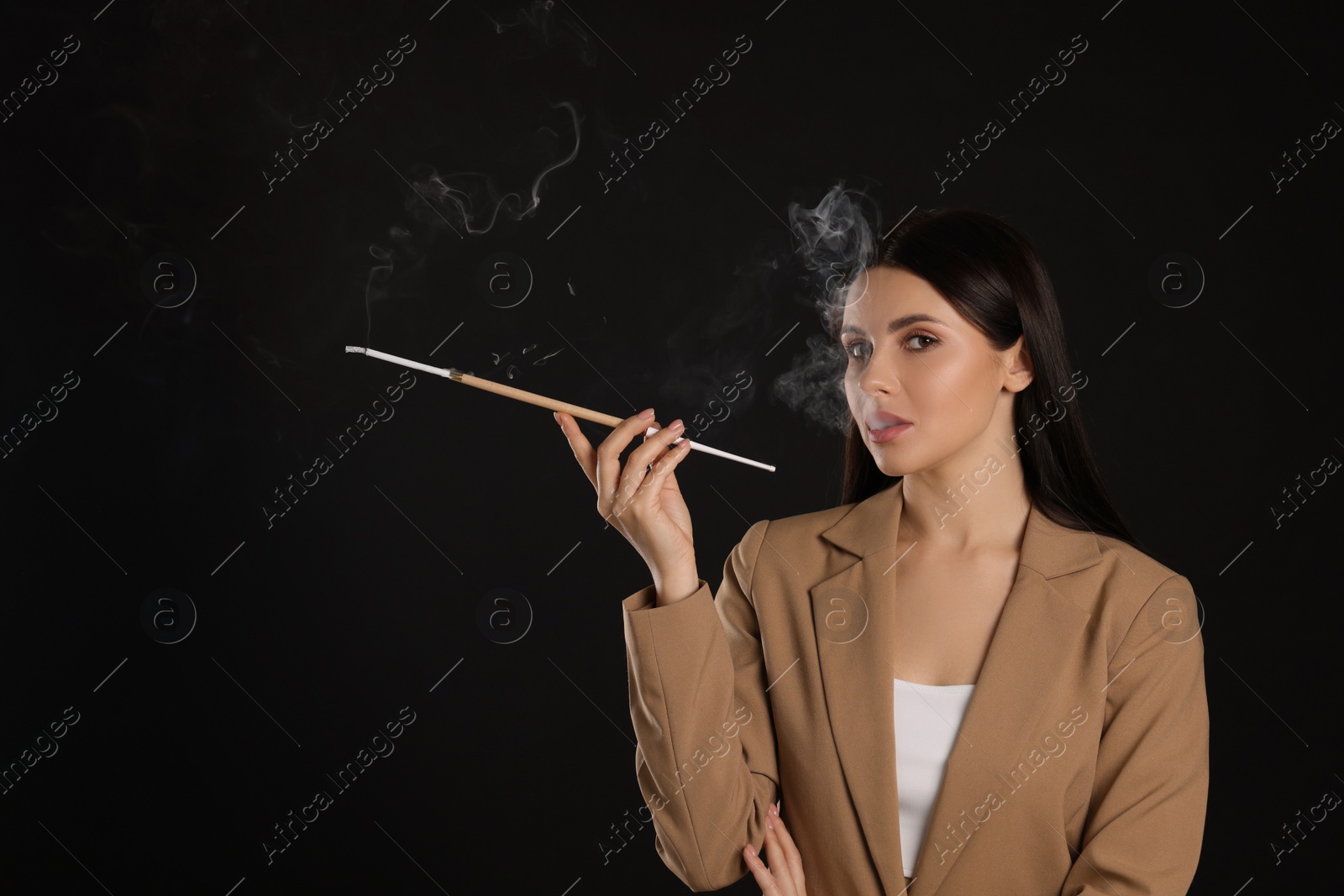 Photo of Woman using long cigarette holder for smoking on black background, space for text