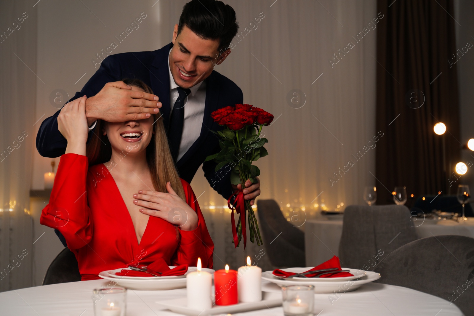 Photo of Man presenting roses to his beloved woman in restaurant at romantic dinner