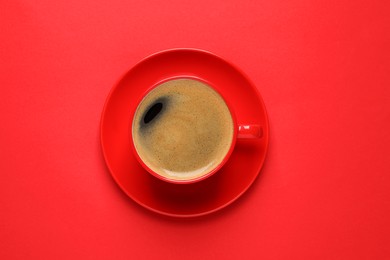 Photo of Cup of aromatic coffee on red background, top view