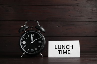 Image of Business lunch concept. Card with phrase Lunch Time and black alarm clock on wooden table