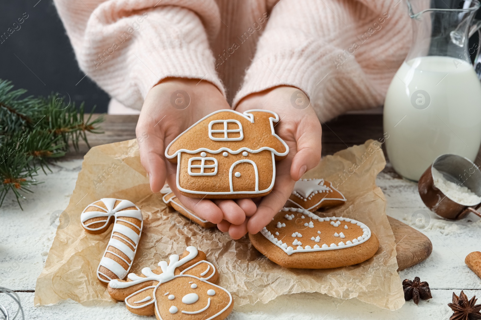 Photo of Woman holding delicious homemade Christmas cookie at wooden table, closeup