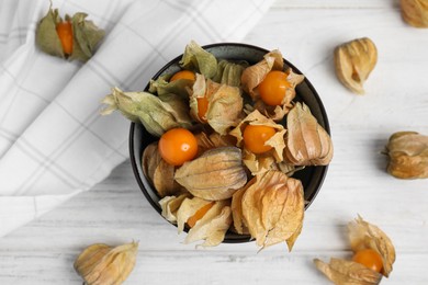 Photo of Ripe physalis fruits with dry husk on white wooden table, flat lay