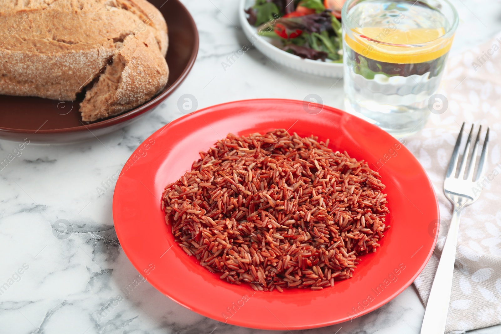 Photo of Tasty brown rice served on white marble table