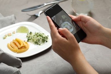 Blogger taking picture of dinner at grey table, closeup