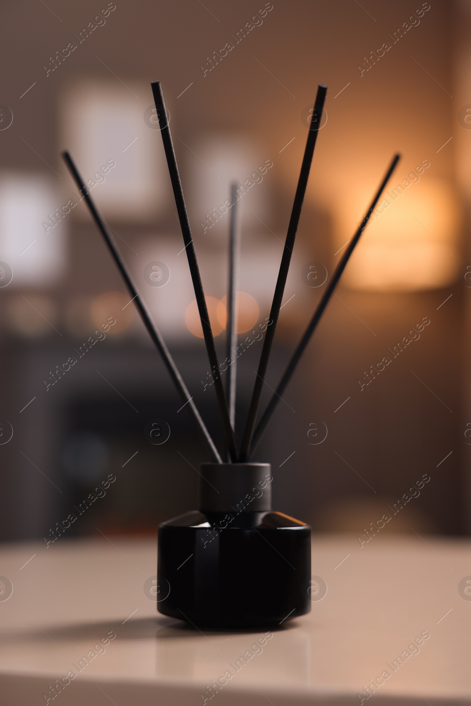 Photo of Reed diffuser on white table indoors. Cozy atmosphere