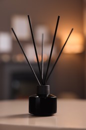Reed diffuser on white table indoors. Cozy atmosphere