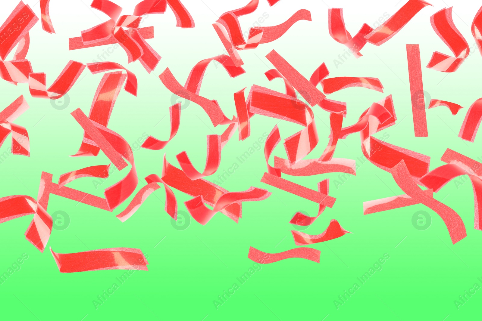 Image of Bright red confetti falling on gradient green background