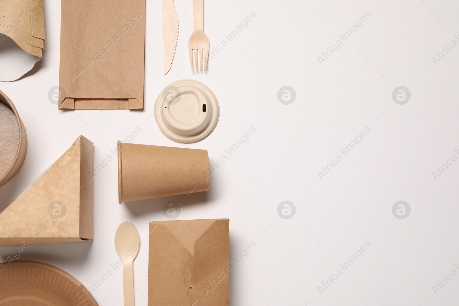 Photo of Eco friendly food packaging. Paper containers, bag and tableware on white background, flat lay. Space for text