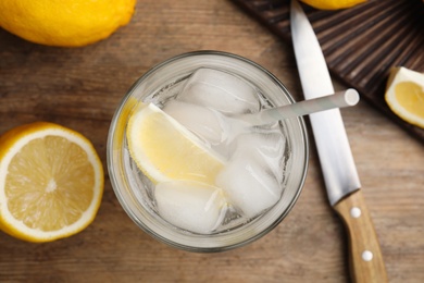 Photo of Soda water with lemon slices and ice cubes on wooden table, flat lay