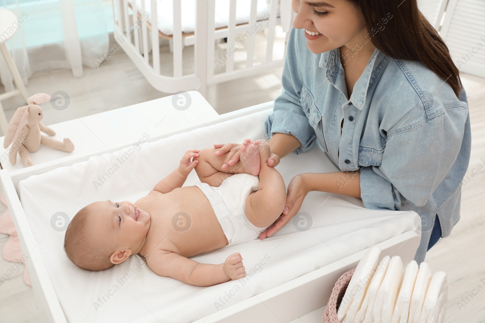 Photo of Mother changing her baby's diaper on table at home