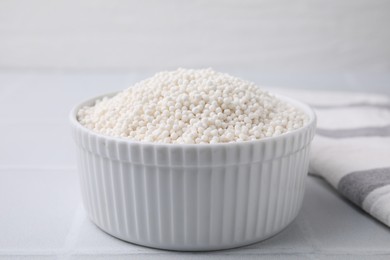 Photo of Tapioca pearls in bowl on white tiled table, closeup