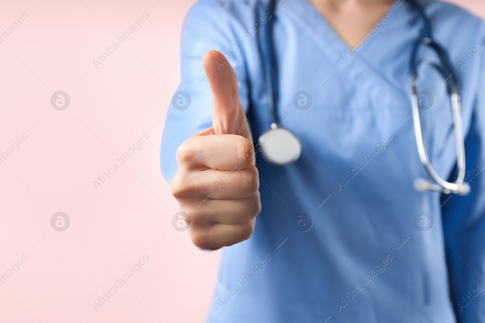 Photo of Doctor with stethoscope on pink background, closeup. Medical service