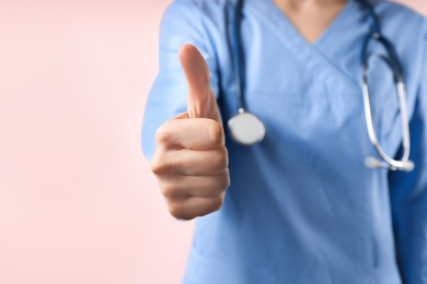 Doctor with stethoscope on pink background, closeup. Medical service