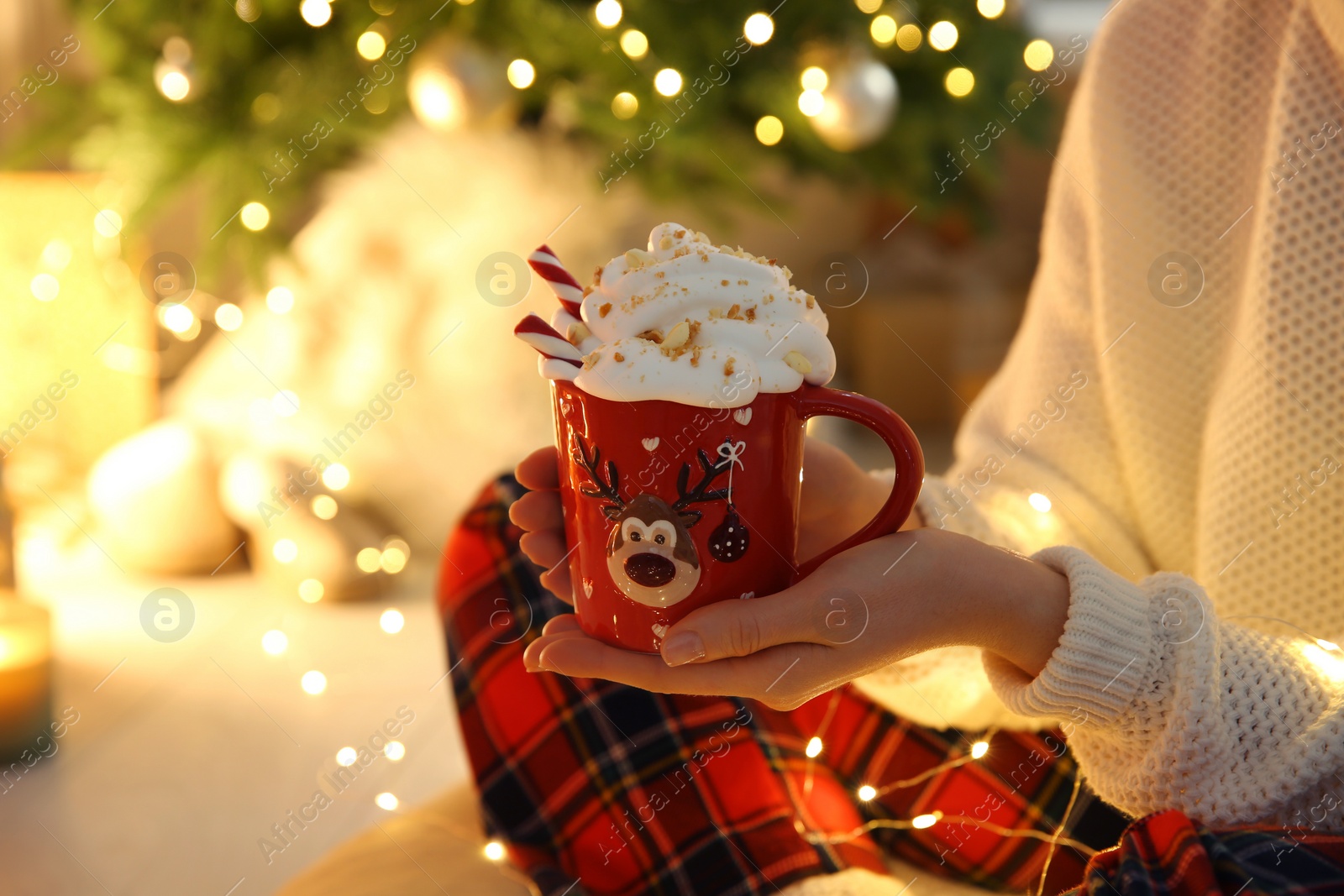 Photo of Woman with cup of hot drink near Christmas tree indoors, closeup