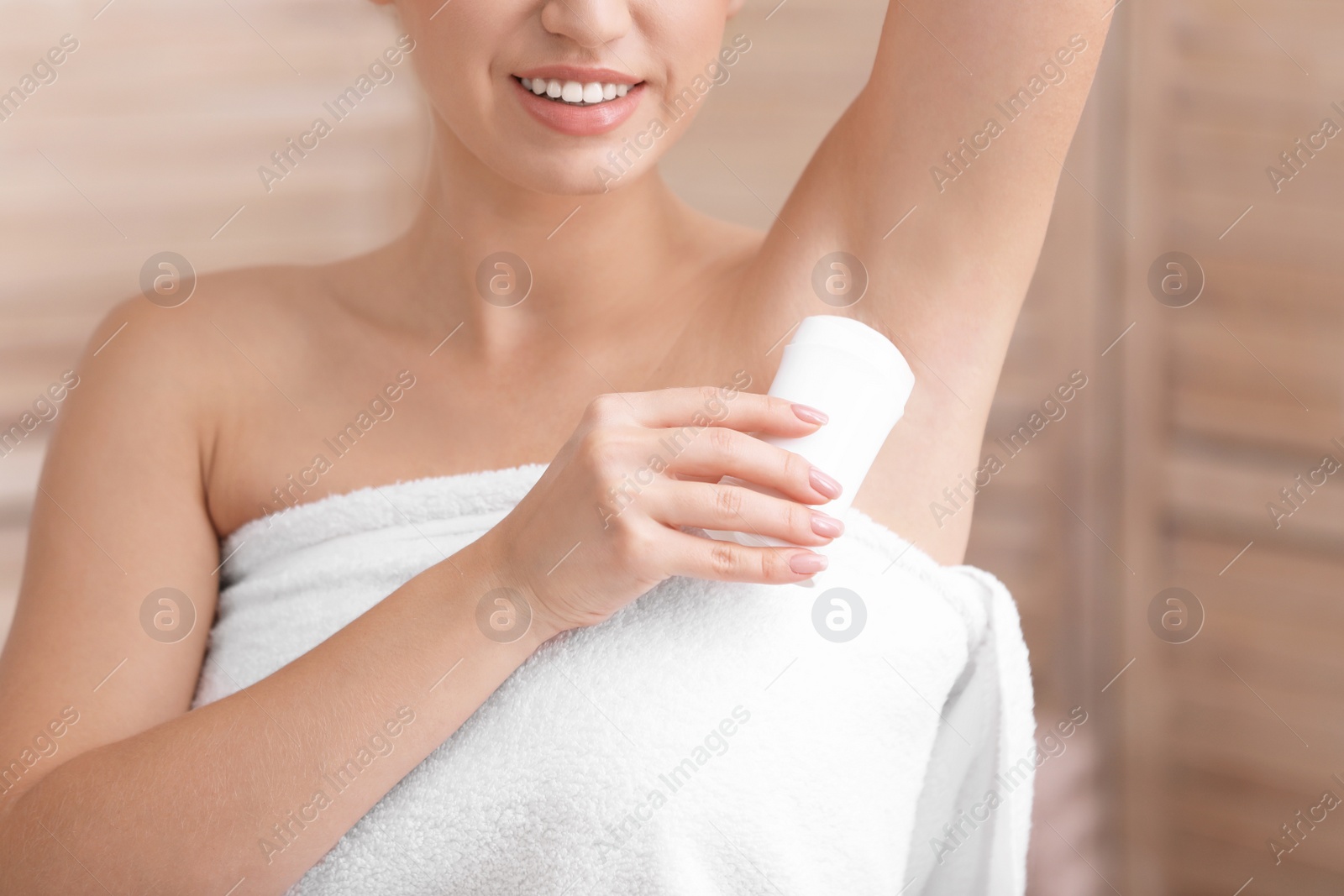 Photo of Beautiful young woman applying deodorant after shower in bathroom