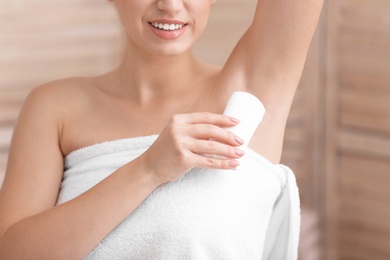 Photo of Beautiful young woman applying deodorant after shower in bathroom