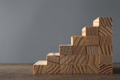 Steps made with wooden blocks on table against grey background, space for text. Career ladder