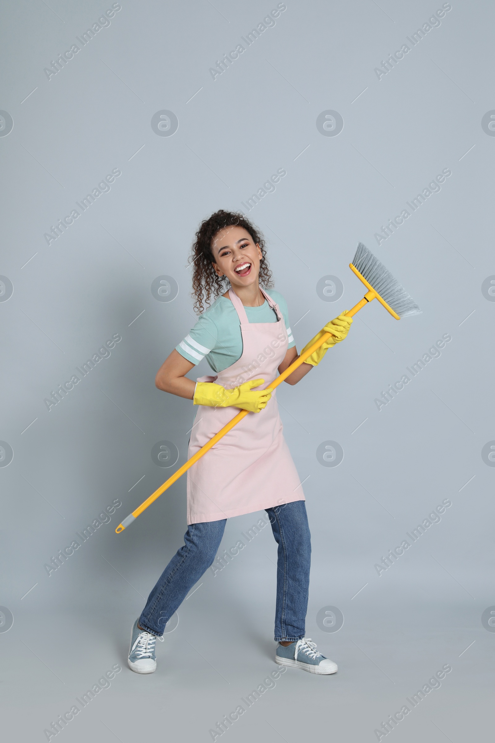 Photo of African American woman with yellow broom on grey background