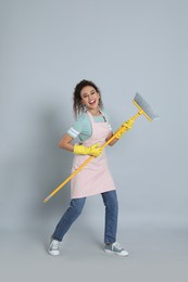 African American woman with yellow broom on grey background