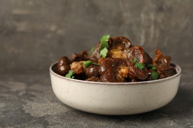 Photo of Bowl with delicious kidneys and parsley on grey table, closeup