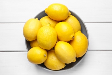 Many fresh ripe lemons on white wooden table, top view