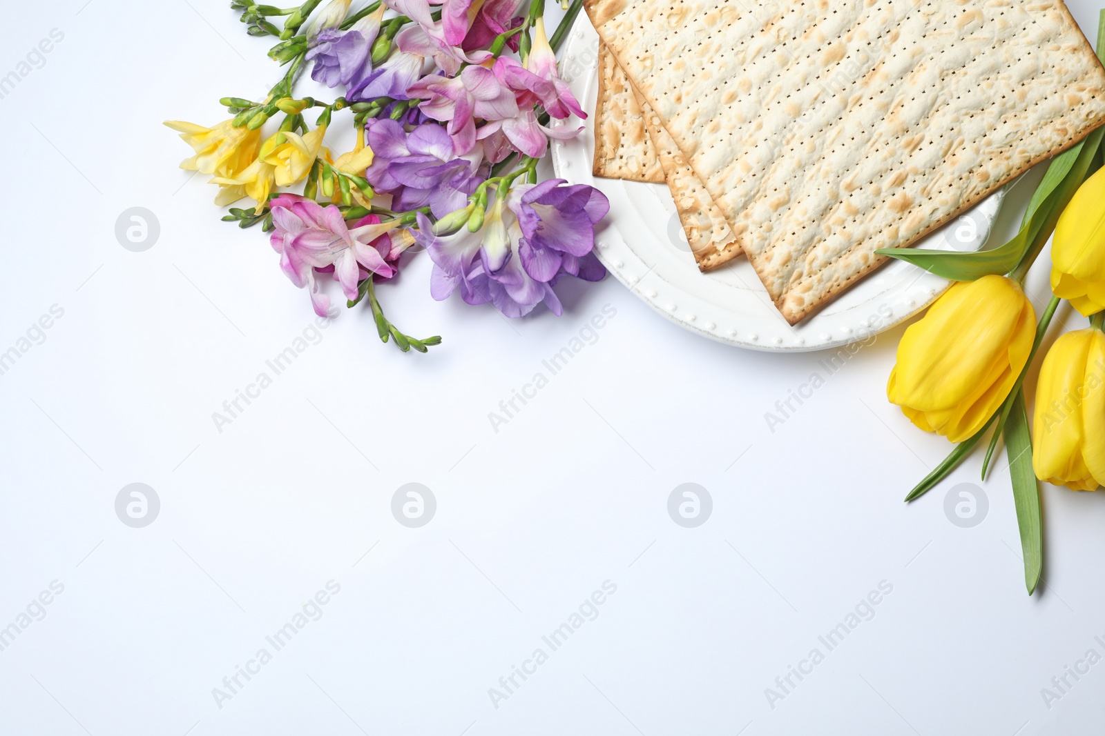 Photo of Composition with matzo and flowers on white background, top view. Passover (Pesach) Seder