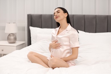 Photo of Pregnant young woman on bed at home
