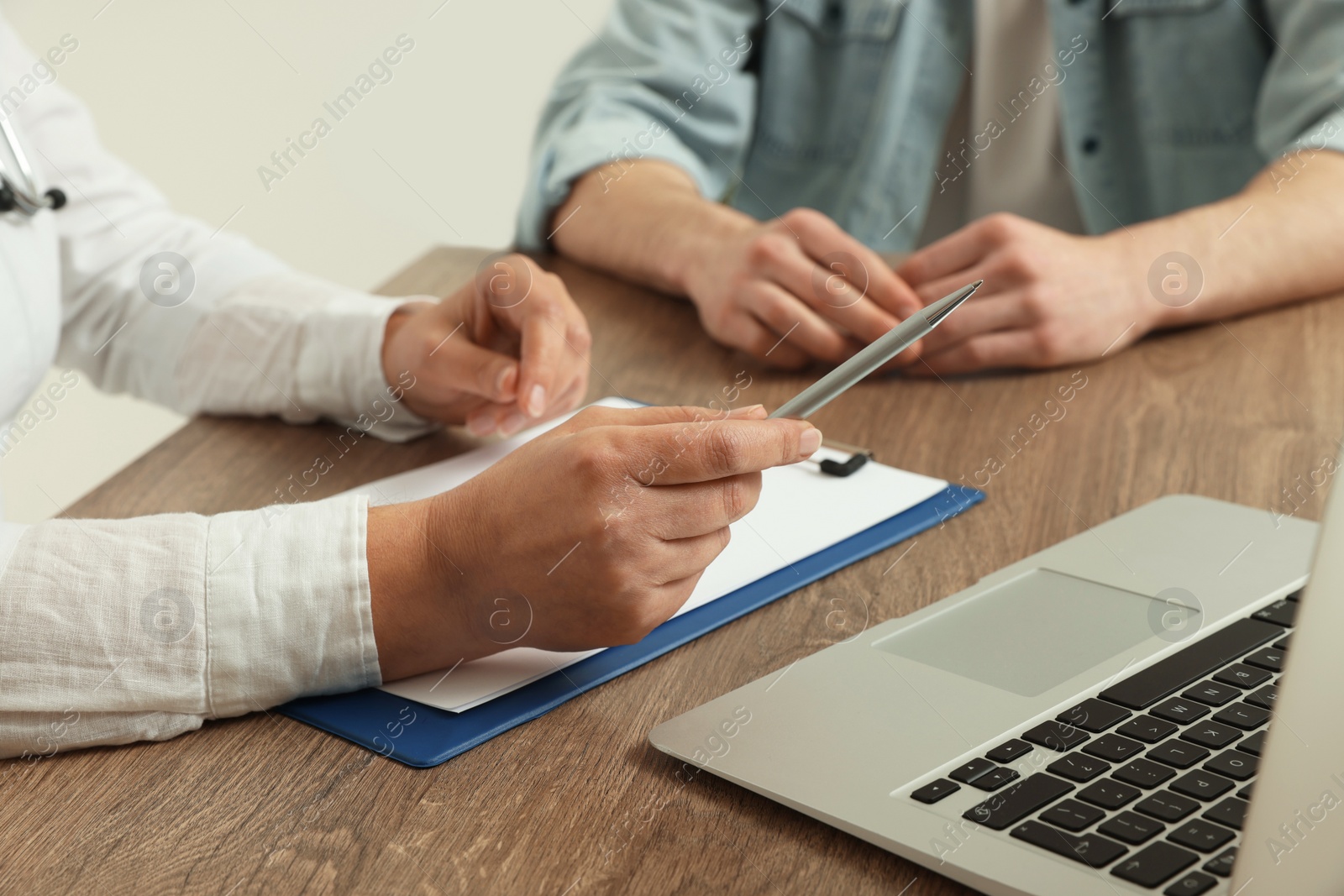 Photo of Professional doctor working with patient at wooden table, closeup