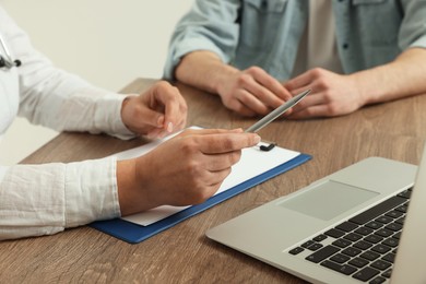 Professional doctor working with patient at wooden table, closeup