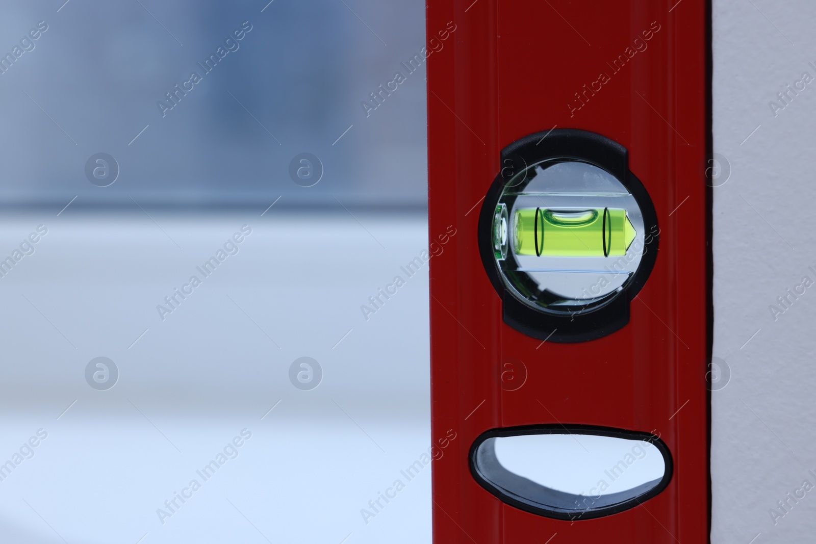 Photo of Red building level on white windowsill indoors, closeup. Space for text