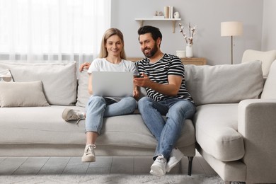 Happy couple with laptop on sofa at home