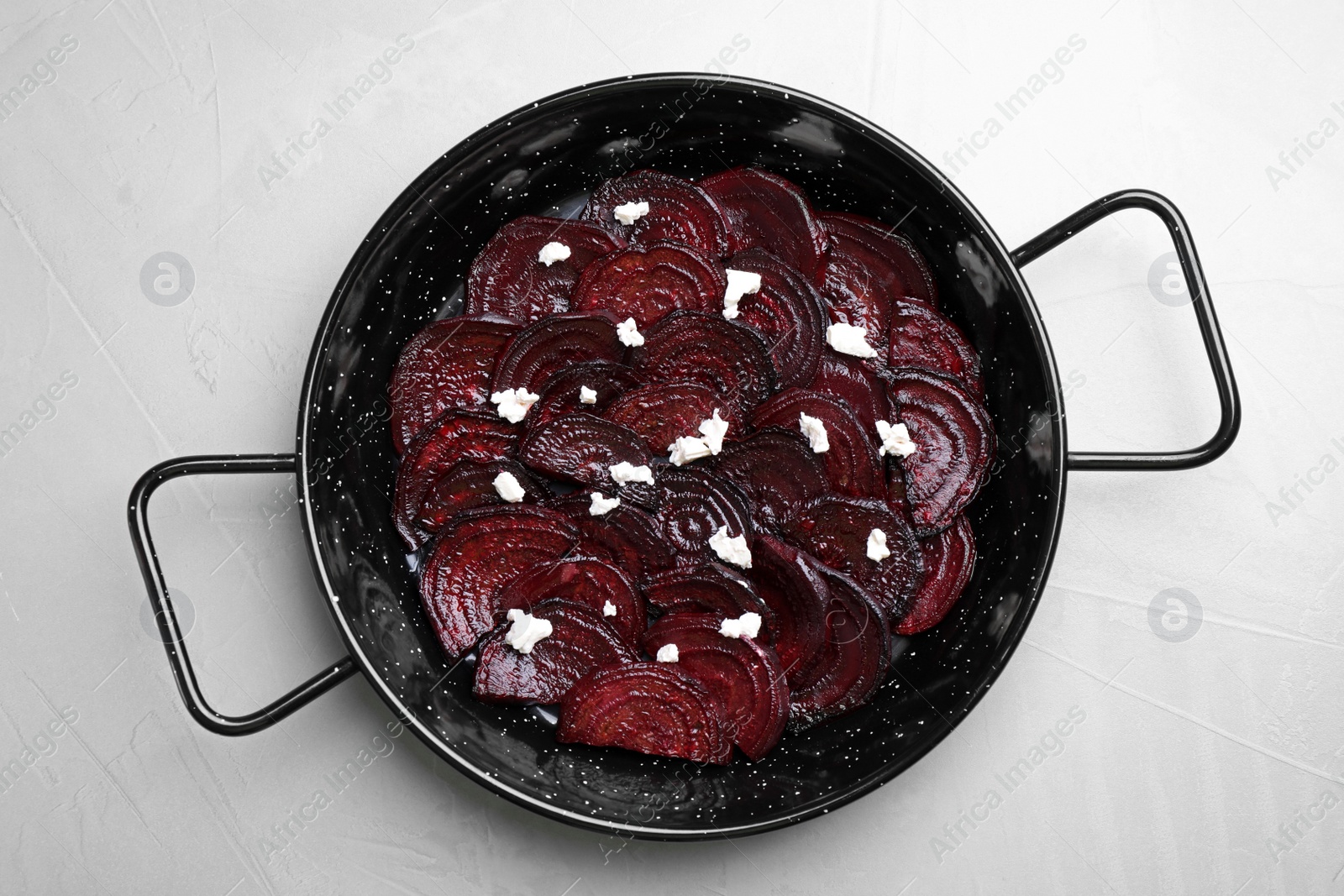 Photo of Roasted beetroot slices with feta cheese in wok pan on light grey table, top view