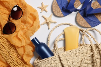 Flat lay composition with wicker bag and other beach accessories on white background
