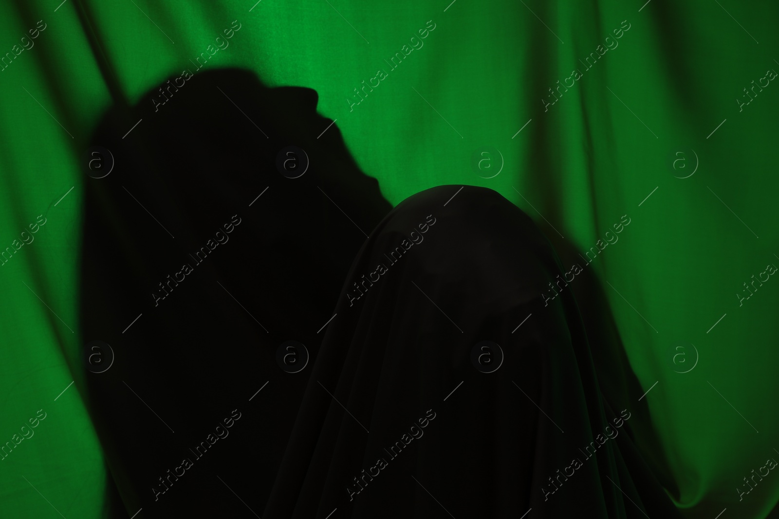 Photo of Silhouette of creepy ghost behind dark green cloth